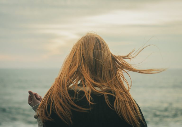 Mujer con el pelo fino mirando al mar