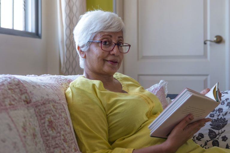 Mujer mayor leyendo un libro en el salón