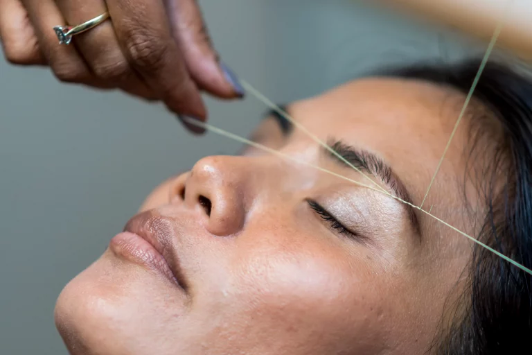 Mujer depilándose las cejas con hilo