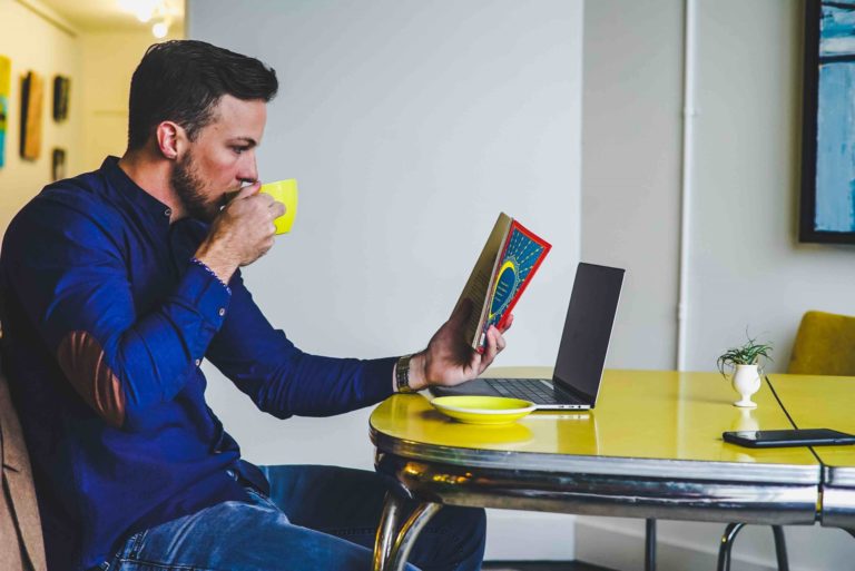 Hombre leyendo un libro mientras se toma un café