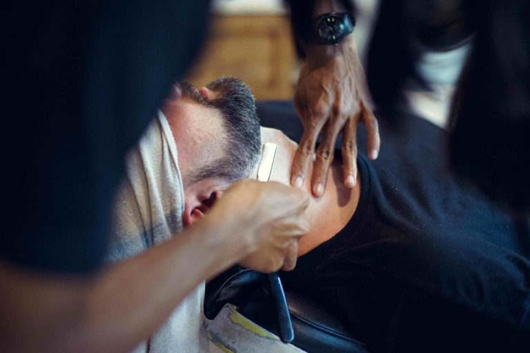 Barbero afeitando a un hombre con cuchilla